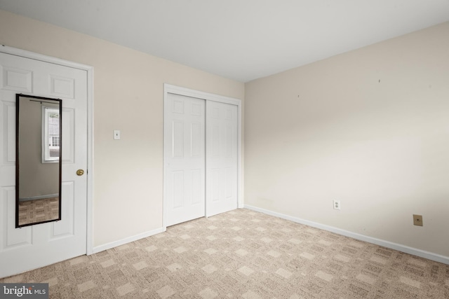 unfurnished bedroom featuring a closet and light colored carpet