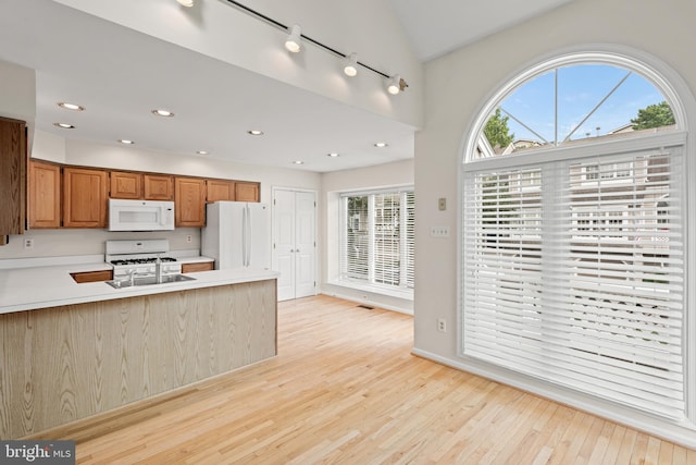 kitchen featuring light hardwood / wood-style flooring, a wealth of natural light, rail lighting, and white appliances