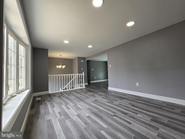 empty room featuring a notable chandelier, wood-type flooring, and a wealth of natural light