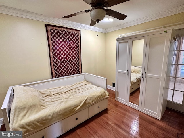 bedroom featuring crown molding, wood-type flooring, ceiling fan, and a closet