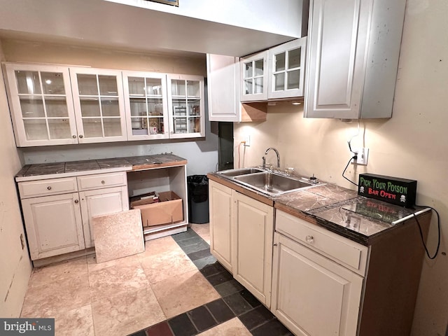 kitchen with white cabinetry, sink, and tile counters