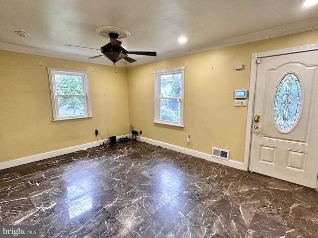 foyer with ornamental molding, a wealth of natural light, and ceiling fan