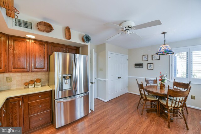 kitchen featuring light wood-type flooring, stainless steel fridge, decorative backsplash, and ceiling fan