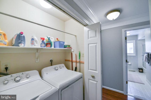 clothes washing area with crown molding, washer and clothes dryer, and dark wood-type flooring