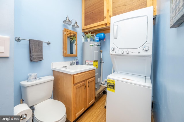 bathroom with electric water heater, stacked washer and clothes dryer, toilet, vanity, and wood-type flooring