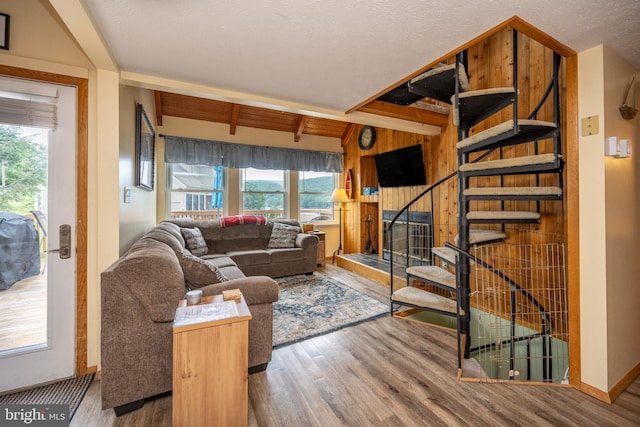 living room with beam ceiling, light hardwood / wood-style flooring, and wooden walls