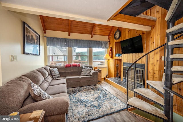 living room featuring hardwood / wood-style flooring, wood walls, vaulted ceiling with beams, and a tile fireplace