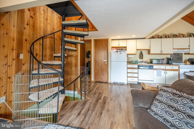 kitchen with wooden walls, light hardwood / wood-style flooring, white appliances, a textured ceiling, and cream cabinets