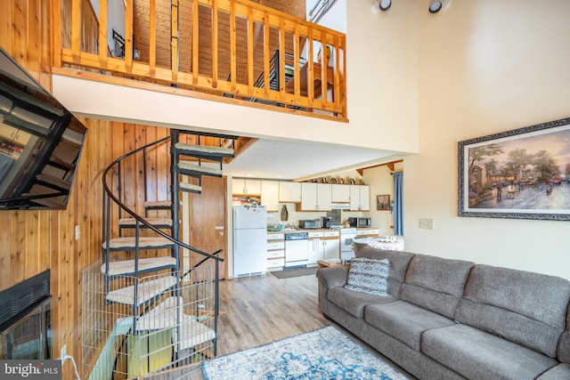 living room with wooden walls, light wood-type flooring, and a high ceiling