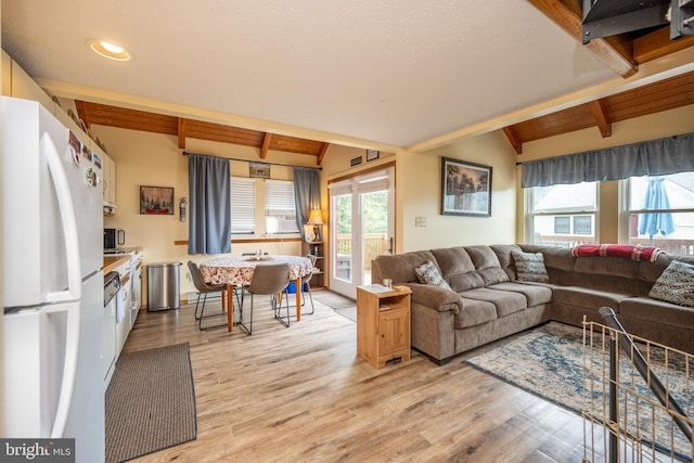 living room featuring light hardwood / wood-style flooring and lofted ceiling with beams