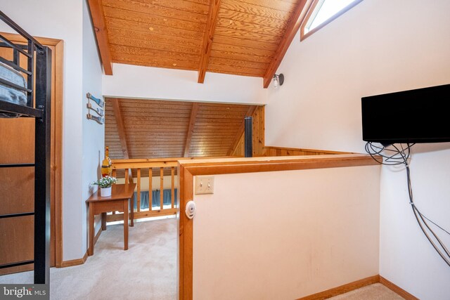 hallway featuring carpet, wooden ceiling, and vaulted ceiling with beams