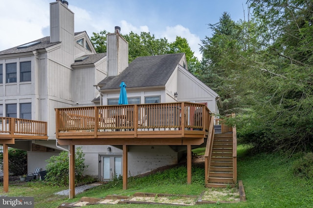 rear view of house featuring a wooden deck and a lawn