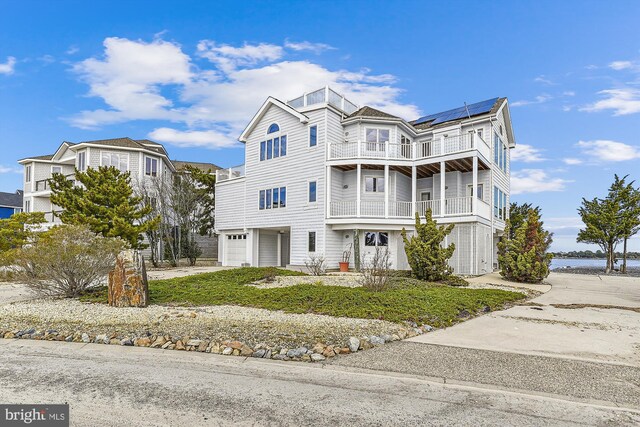 view of front of house featuring a balcony, solar panels, and a garage