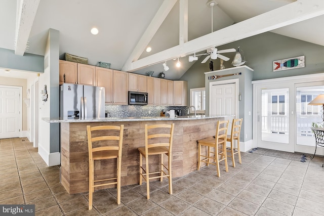 kitchen with light tile patterned floors, a kitchen bar, stainless steel appliances, light countertops, and light brown cabinets