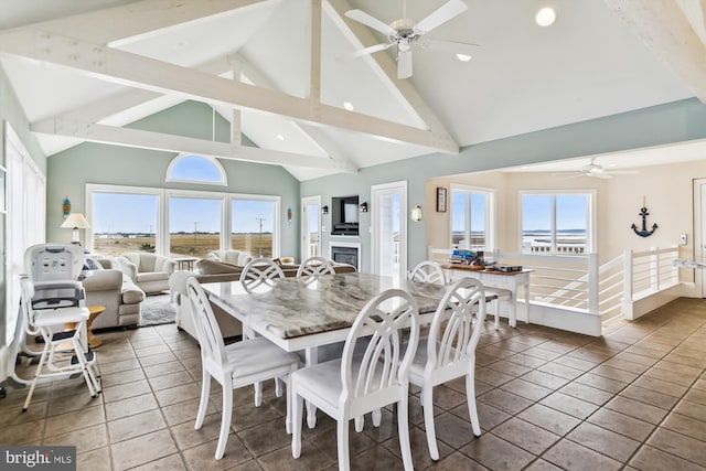 dining space with ceiling fan, beamed ceiling, tile patterned floors, a fireplace, and high vaulted ceiling