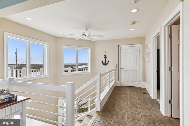 corridor featuring baseboards, an upstairs landing, and recessed lighting