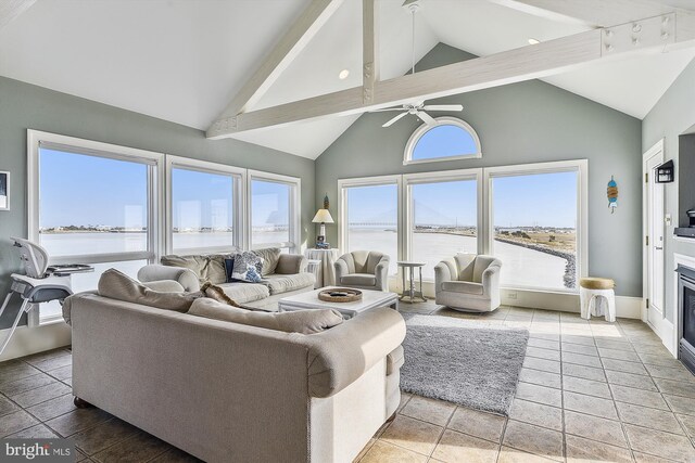 tiled living room featuring ceiling fan, high vaulted ceiling, beamed ceiling, and a water view