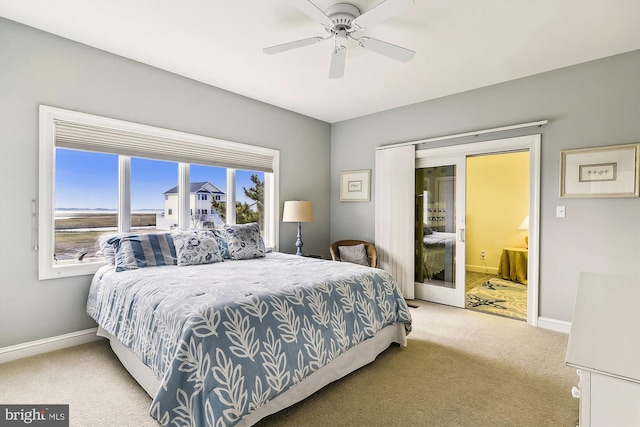 bedroom featuring baseboards, ensuite bathroom, a ceiling fan, and light colored carpet