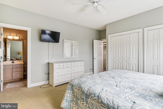 carpeted bedroom featuring ceiling fan, two closets, and ensuite bathroom