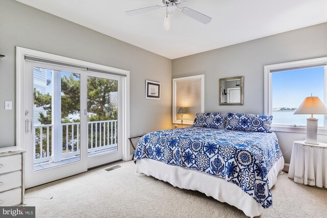 carpeted bedroom featuring ceiling fan, a water view, and access to exterior