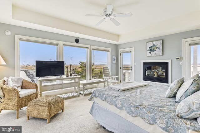 carpeted bedroom with ceiling fan and a raised ceiling