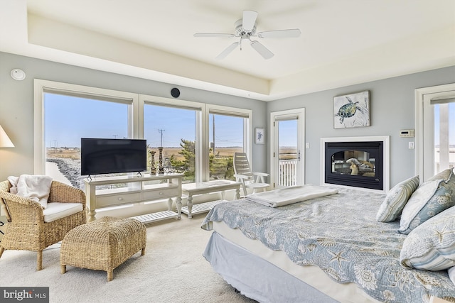 bedroom featuring access to outside, multiple windows, a glass covered fireplace, and carpet