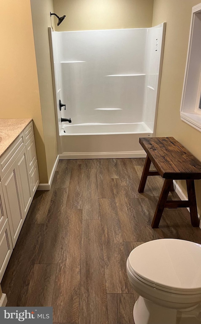 full bathroom with hardwood / wood-style floors, bathing tub / shower combination, vanity, and toilet