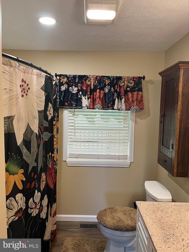 bathroom featuring vanity, a textured ceiling, hardwood / wood-style floors, and toilet