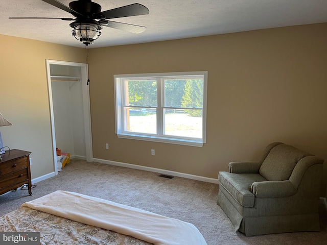 living area with light carpet, ceiling fan, and a textured ceiling