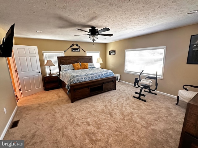 carpeted bedroom featuring ceiling fan and a textured ceiling