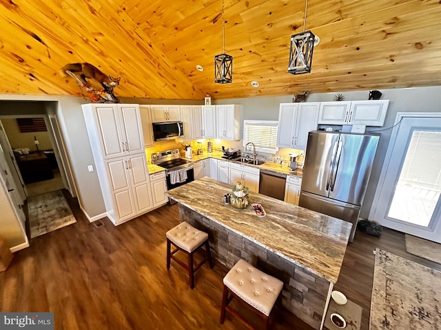 kitchen featuring vaulted ceiling, light stone countertops, pendant lighting, and stainless steel appliances