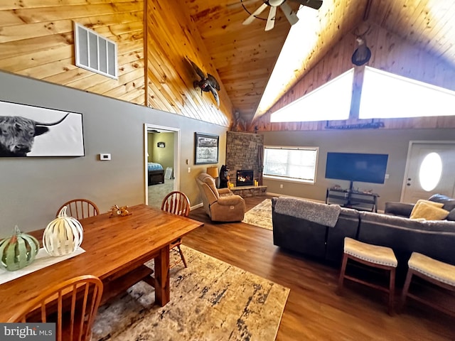 dining room with ceiling fan, wood ceiling, vaulted ceiling, a fireplace, and hardwood / wood-style floors