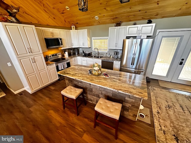 kitchen with white cabinetry, appliances with stainless steel finishes, dark hardwood / wood-style floors, wooden ceiling, and light stone countertops