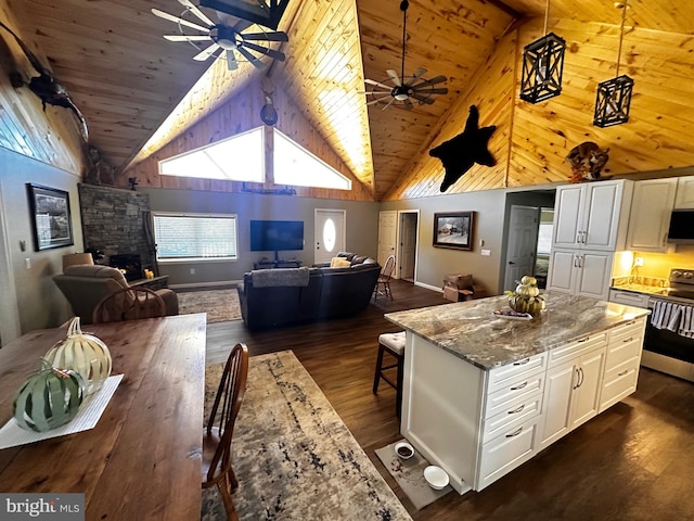 kitchen featuring ceiling fan, white cabinets, light stone countertops, and a fireplace