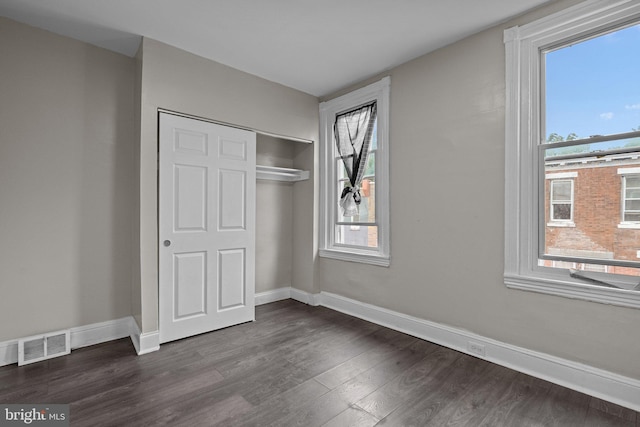 unfurnished bedroom with dark wood-type flooring and a closet