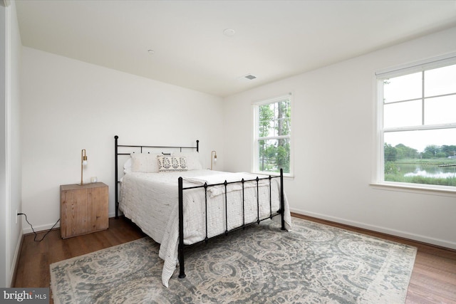 bedroom featuring wood-type flooring and a water view