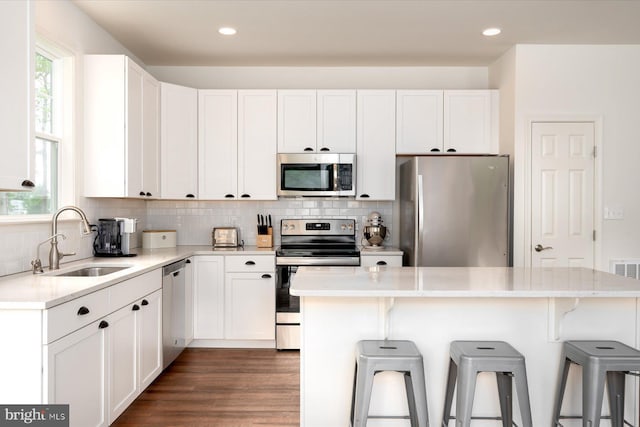 kitchen with white cabinetry, stainless steel appliances, a center island, and sink