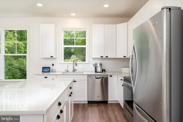 kitchen with sink, white cabinets, dark hardwood / wood-style flooring, stainless steel appliances, and light stone countertops