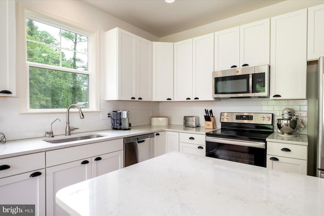 kitchen featuring tasteful backsplash, appliances with stainless steel finishes, sink, and white cabinets