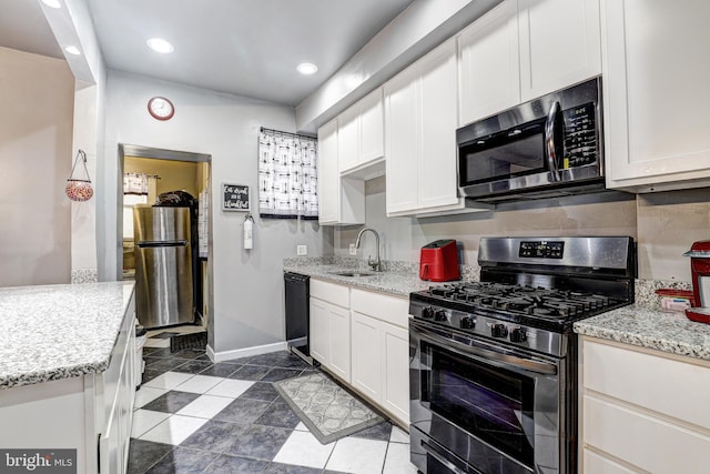 kitchen with white cabinetry, sink, light stone counters, and stainless steel appliances