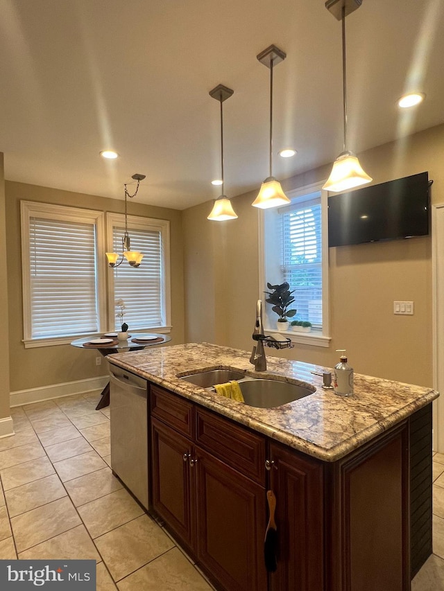 kitchen featuring dishwasher, light tile patterned floors, sink, decorative light fixtures, and an island with sink