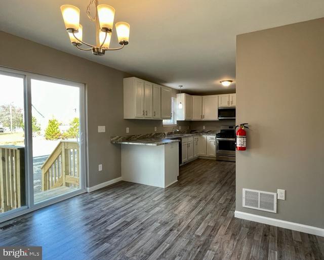 kitchen featuring stainless steel appliances, dark wood-type flooring, pendant lighting, and white cabinets