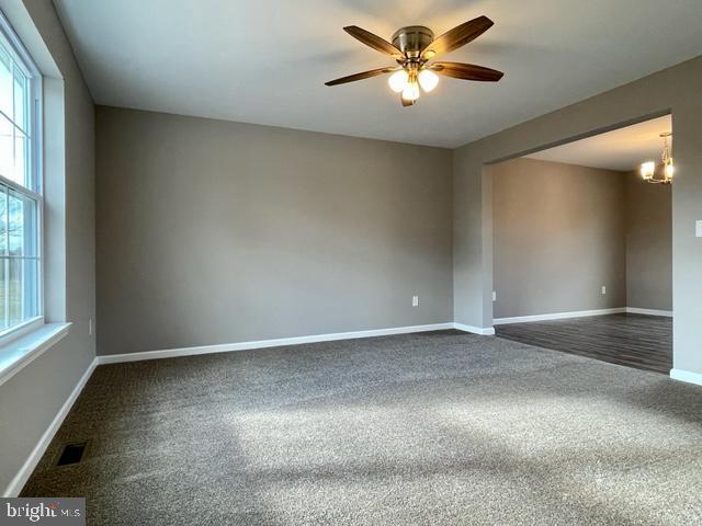 unfurnished room with ceiling fan with notable chandelier