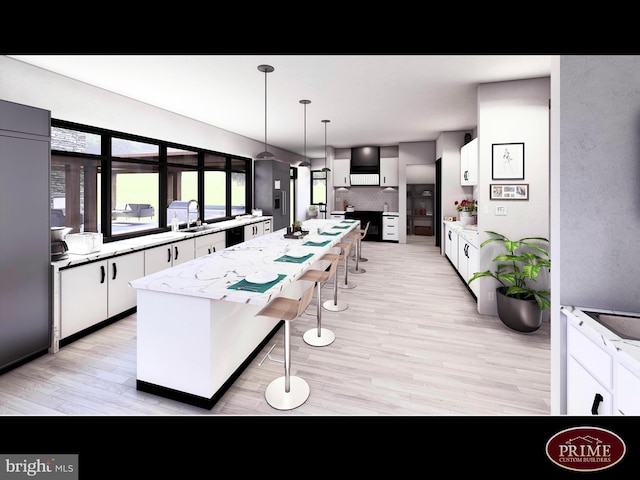 kitchen with white cabinetry, light wood-type flooring, a kitchen breakfast bar, decorative light fixtures, and a center island with sink