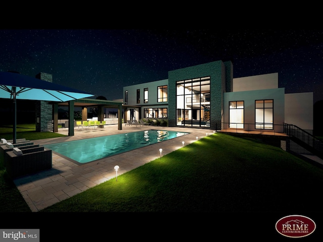 pool at night featuring a patio