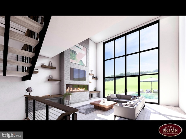 living room with a high ceiling, wood-type flooring, and a large fireplace