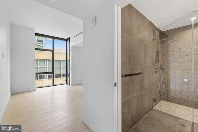 bathroom featuring a wall of windows and tiled shower