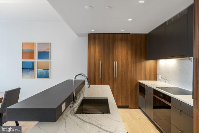 kitchen featuring sink, oven, decorative backsplash, black electric stovetop, and light hardwood / wood-style floors