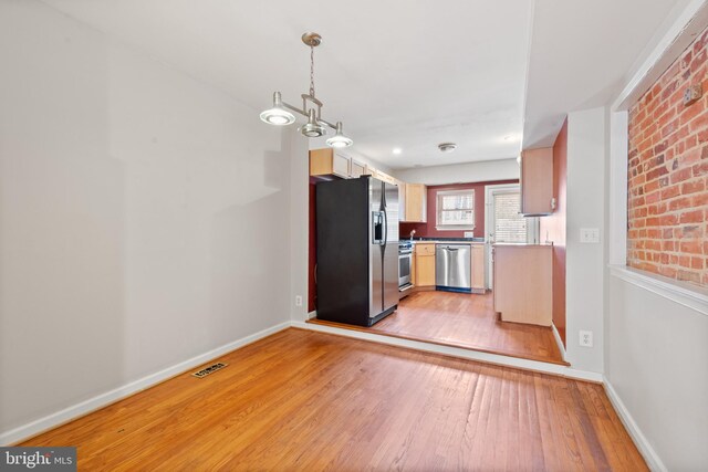 unfurnished bedroom featuring ceiling fan, hardwood / wood-style flooring, a closet, and brick wall