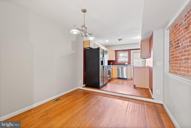 kitchen featuring decorative light fixtures, stainless steel appliances, and light hardwood / wood-style floors